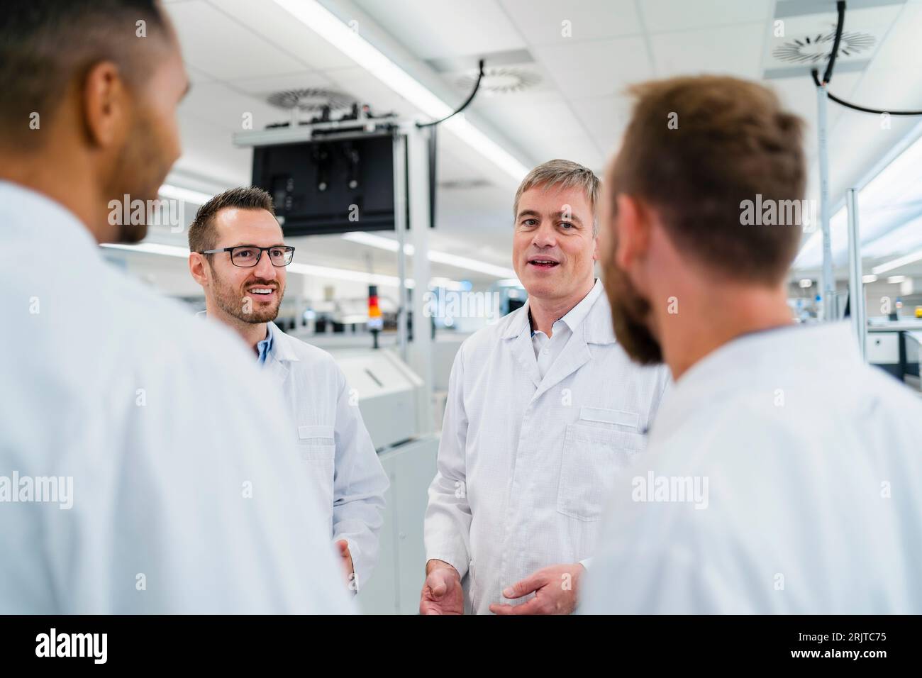 Team of competent electrical technicians in lab coats having meeting in ...