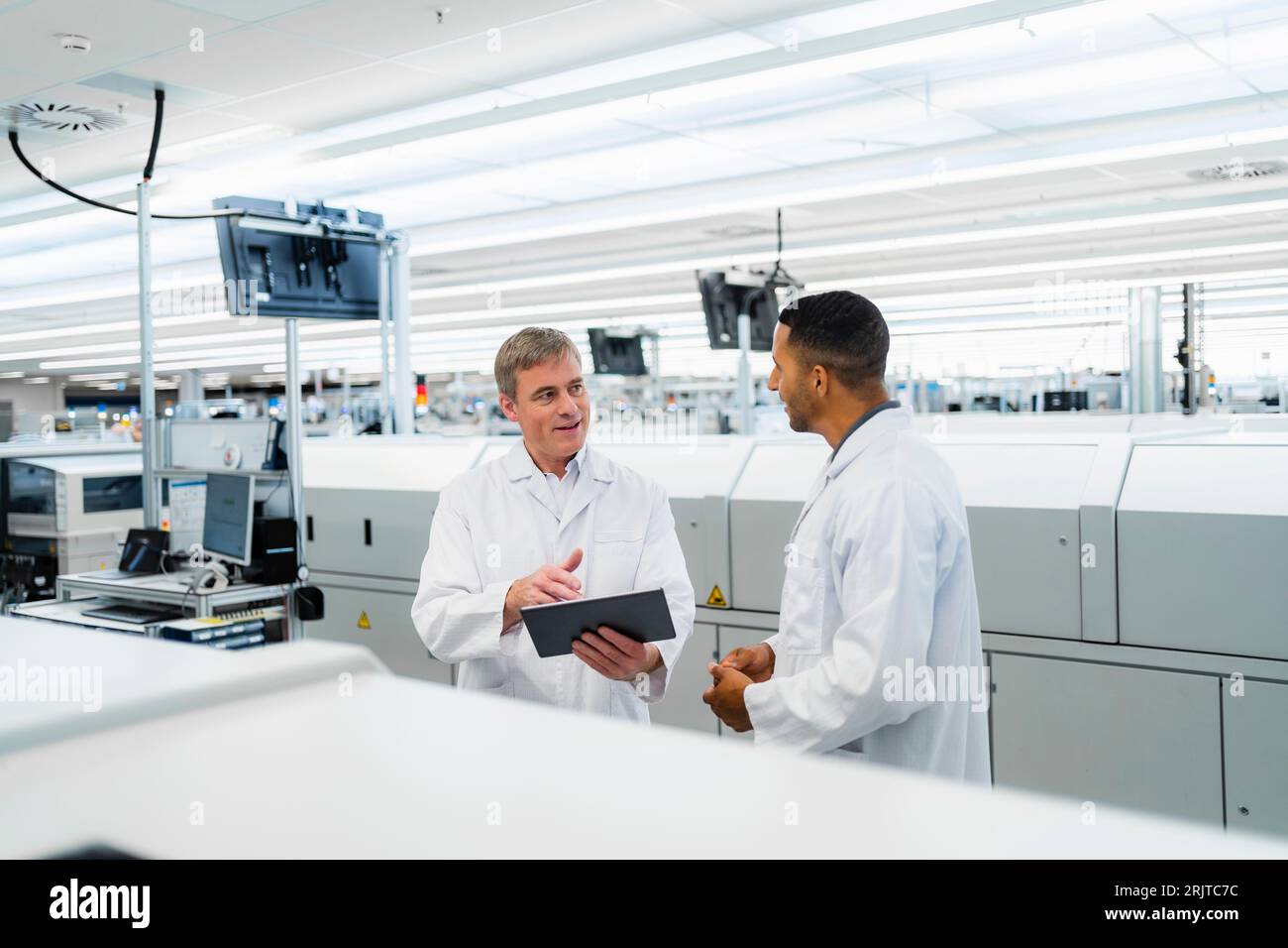 Team of competent electrical technicians in lab coats having meeting in ...