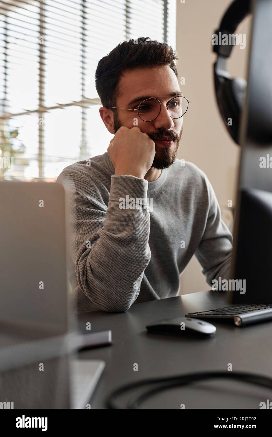 Thoughtful IT professional using desktop computer in office Stock Photo