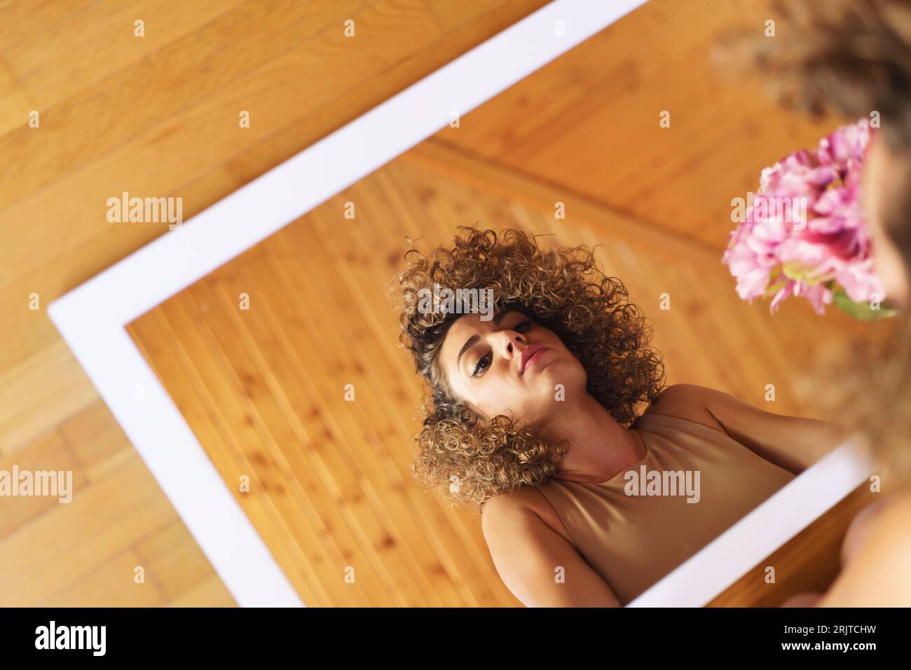 Reflection of woman on mirror with bunch of flowers at home Stock Photo