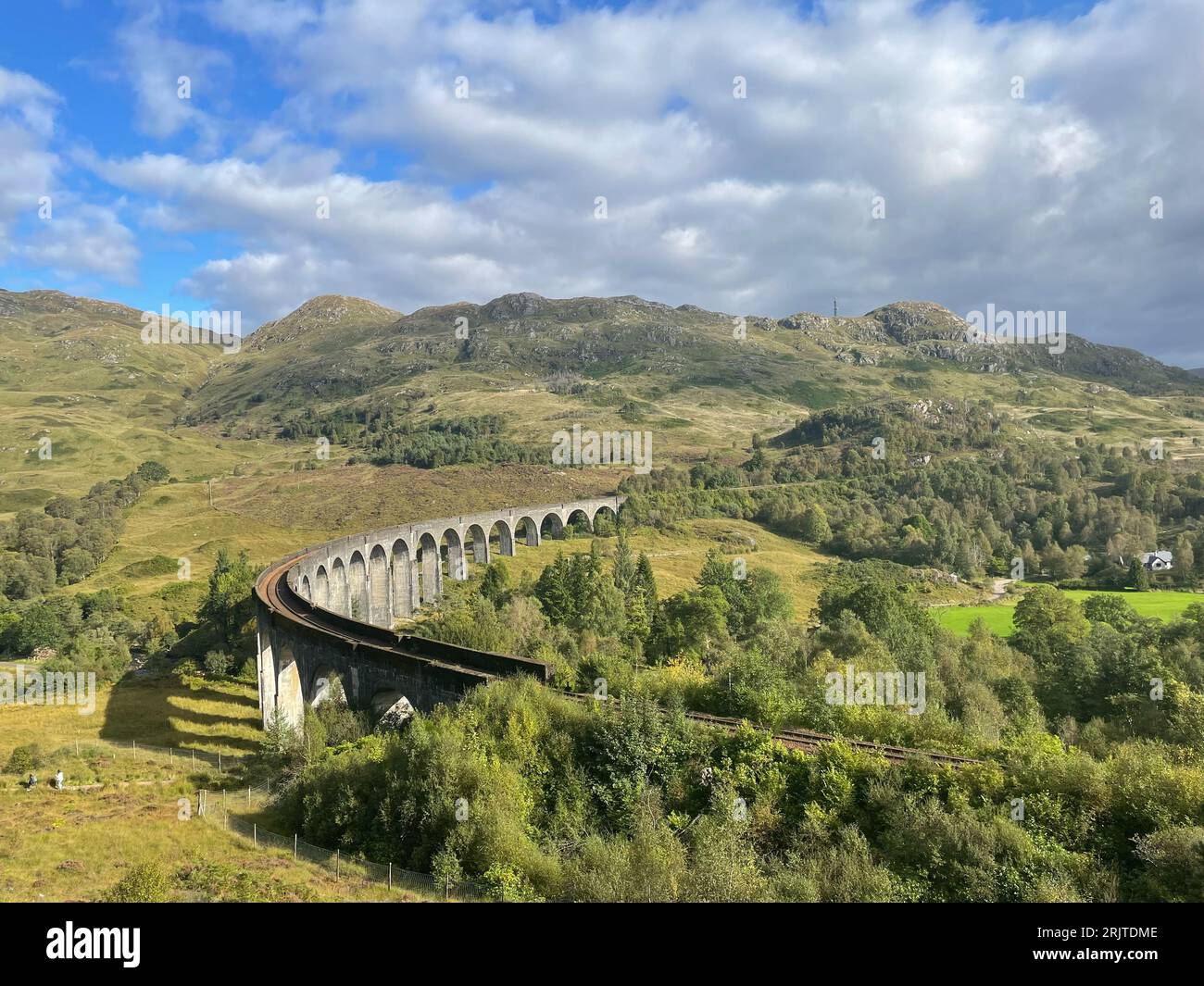 A scenic view of a bridge with lush green grass surrounding it: Scotland, Glenfinnan Viaduct Stock Photo