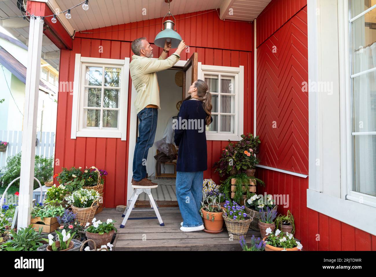Man and woman changing lamp light standing on porch Stock Photo