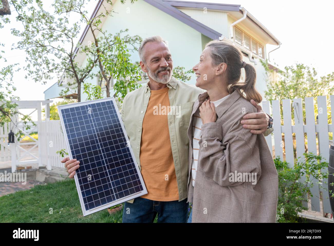 Happy couple with solar panel in front of house Stock Photo