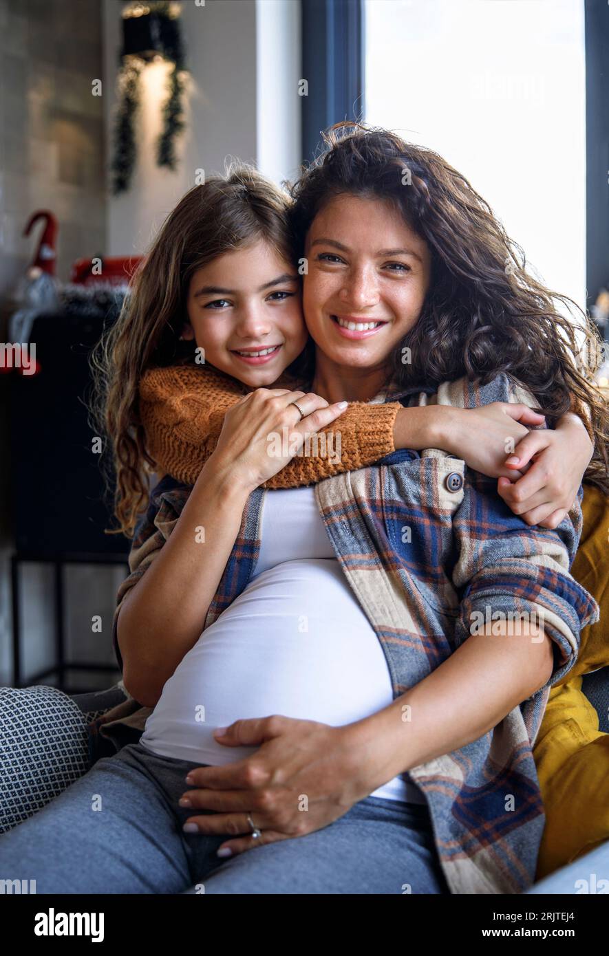 Happy daughter embracing expectant mother at home Stock Photo