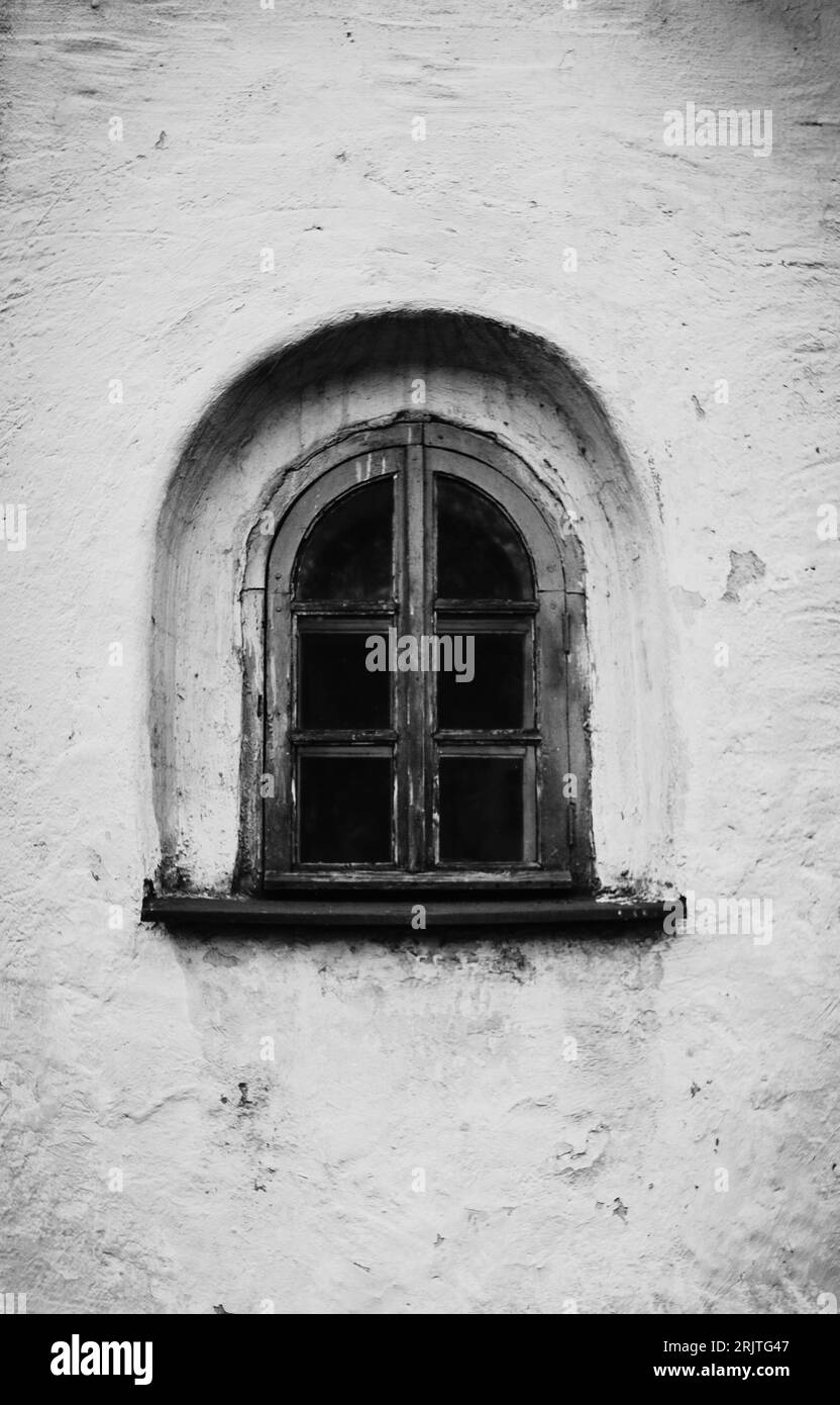 This black and white photograph captures a small, vintage window with