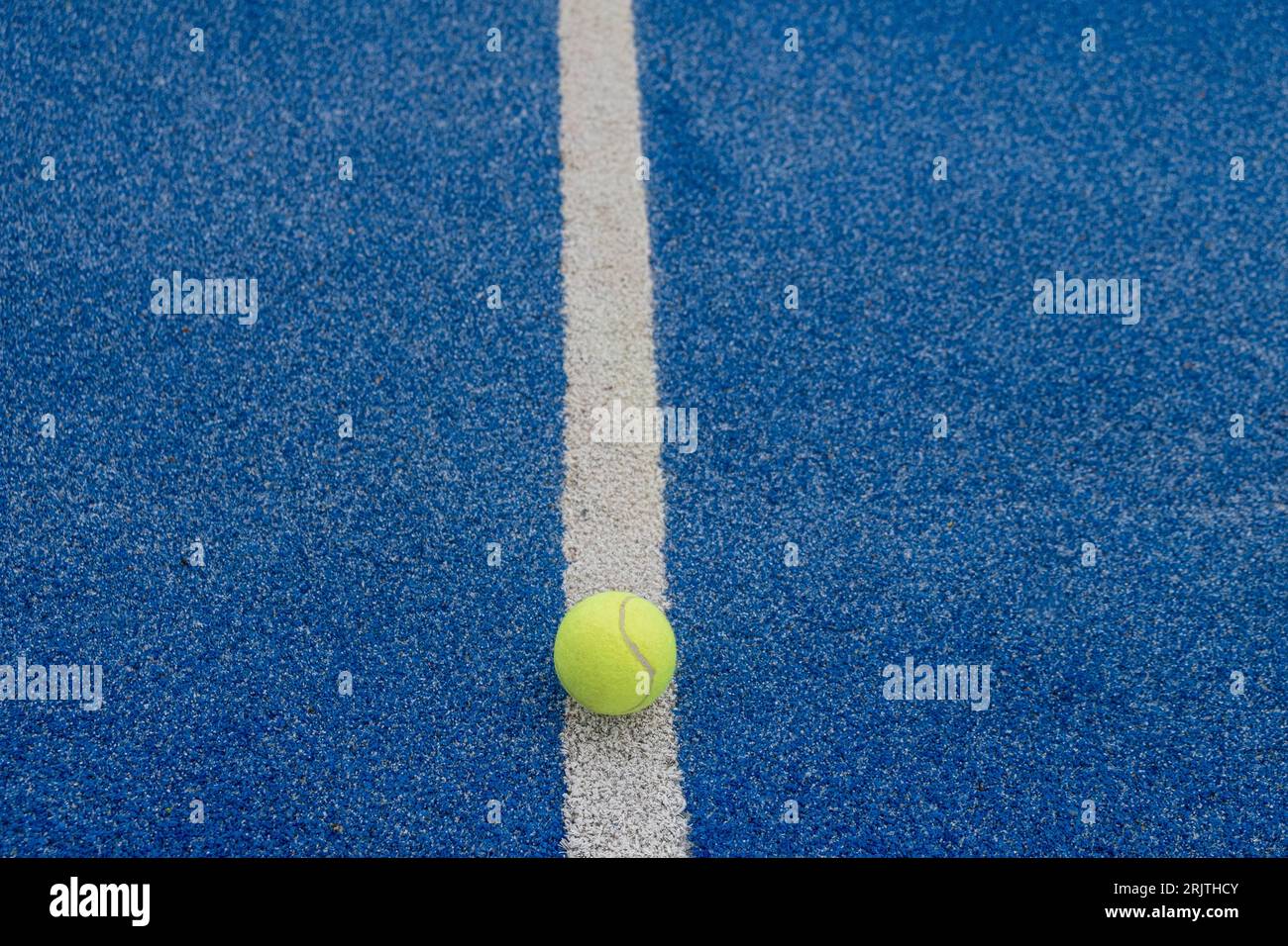 a ball on the dividing line of a blue paddle tennis court Stock Photo ...