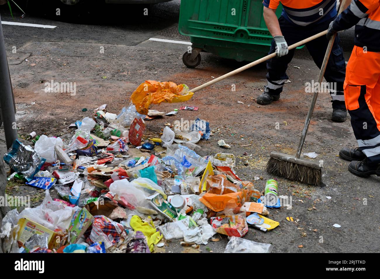 Council workmen clearing up rubbish with shovel and broom fly tipped on