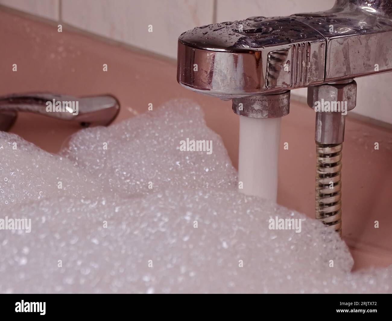 Pink Bathtub Filled to the Brim Metallic Tap Flows with Water and