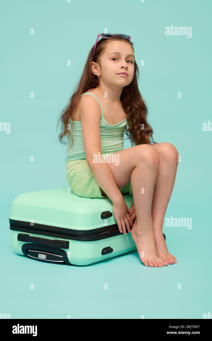 barefoot little model Full length vertical emotional portrait of a charming little kid girl in  summer wear, sitting barefoot on her suitcase, smiling looking at camera,  goi Stock Photo - Alamy