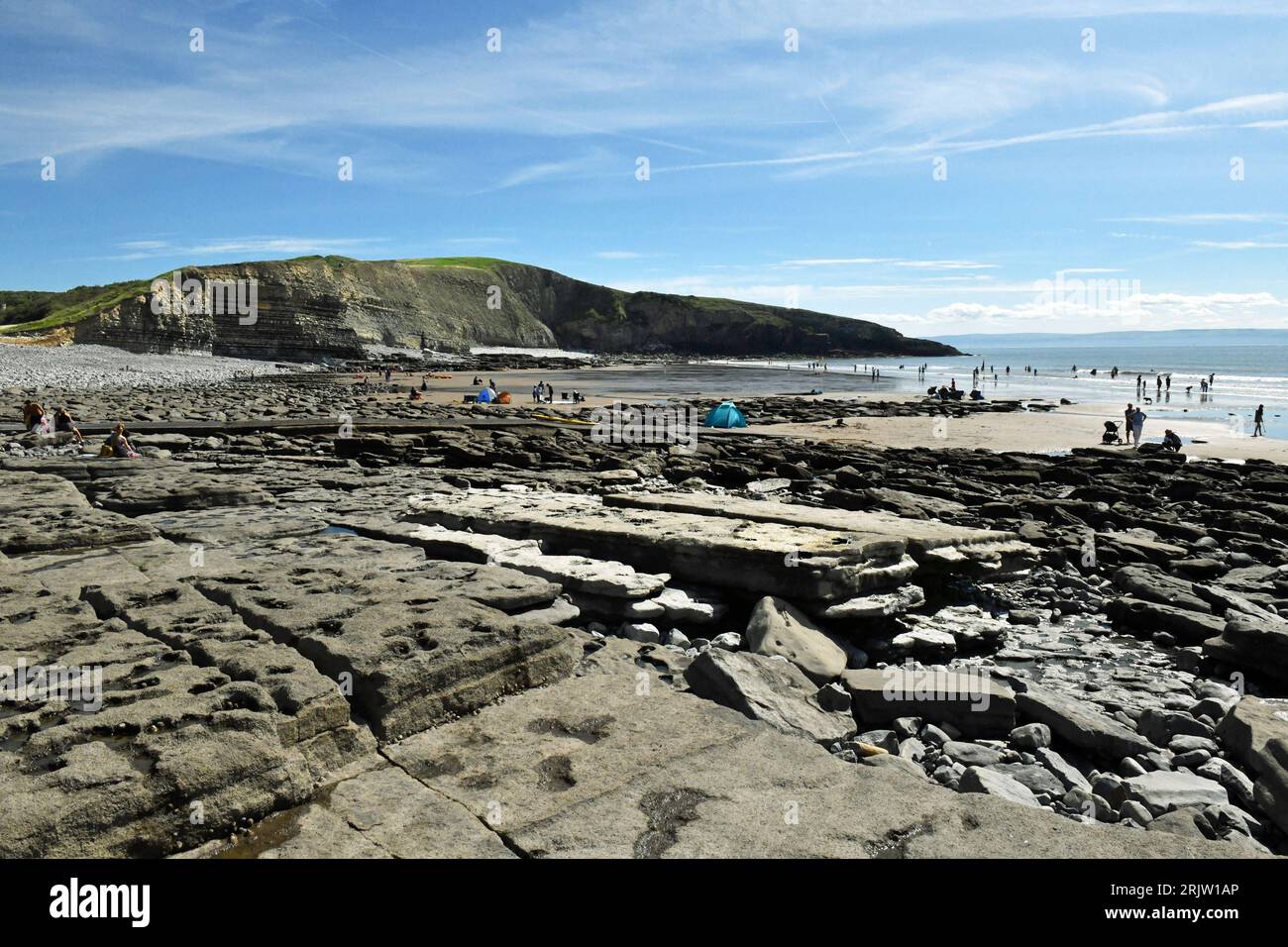 Eye Level view across Dunraven Bay showing rock slabs, Witches Nose, the Beach, the Sea and beach people  - in the Glamorgan Heritage Coast Area Stock Photo