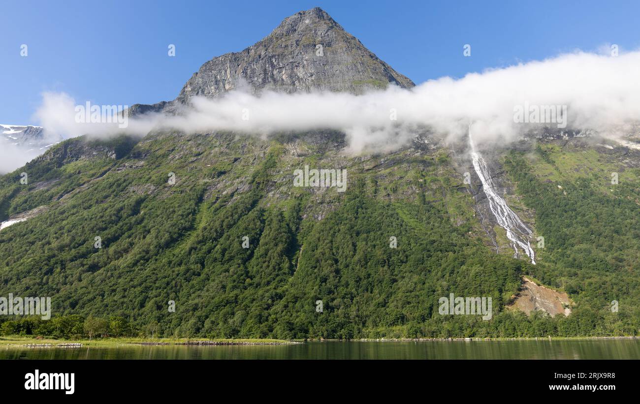 A scenic landscape of a majestic mountain surrounded by a tranquil body ...