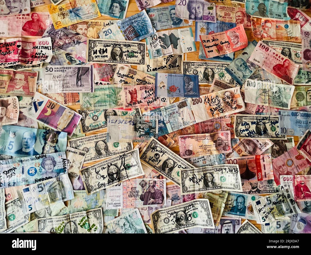 Collection of paper currency from around the world pinned to a bulletin board. Stock Photo