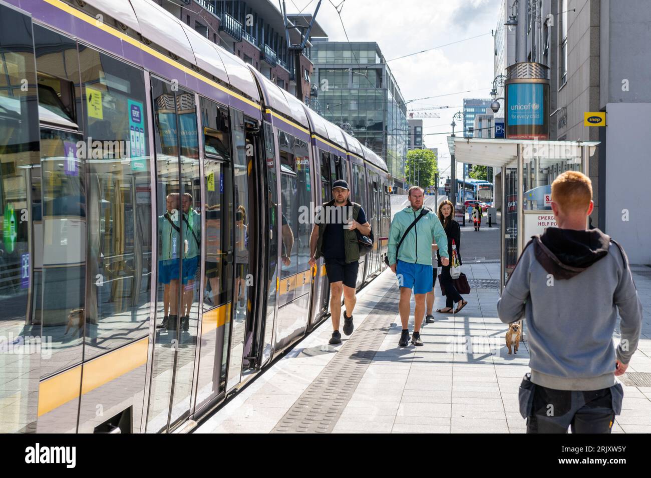 People on a Luas tram station platform boarding a tram in Dublin, Ireland. Stock Photo