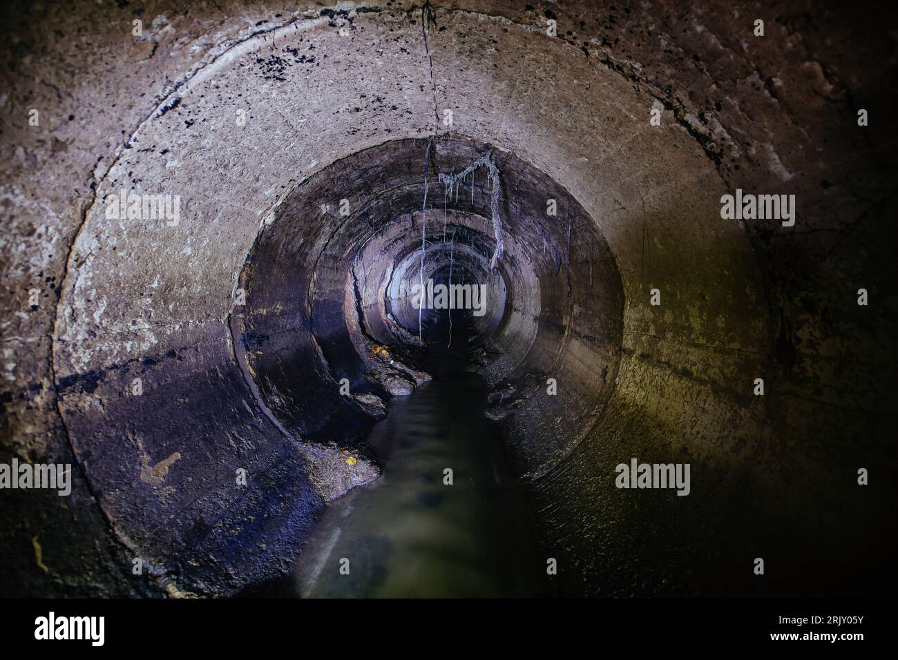 Inside underground urban sewer system. Sewage flowing in round sewer