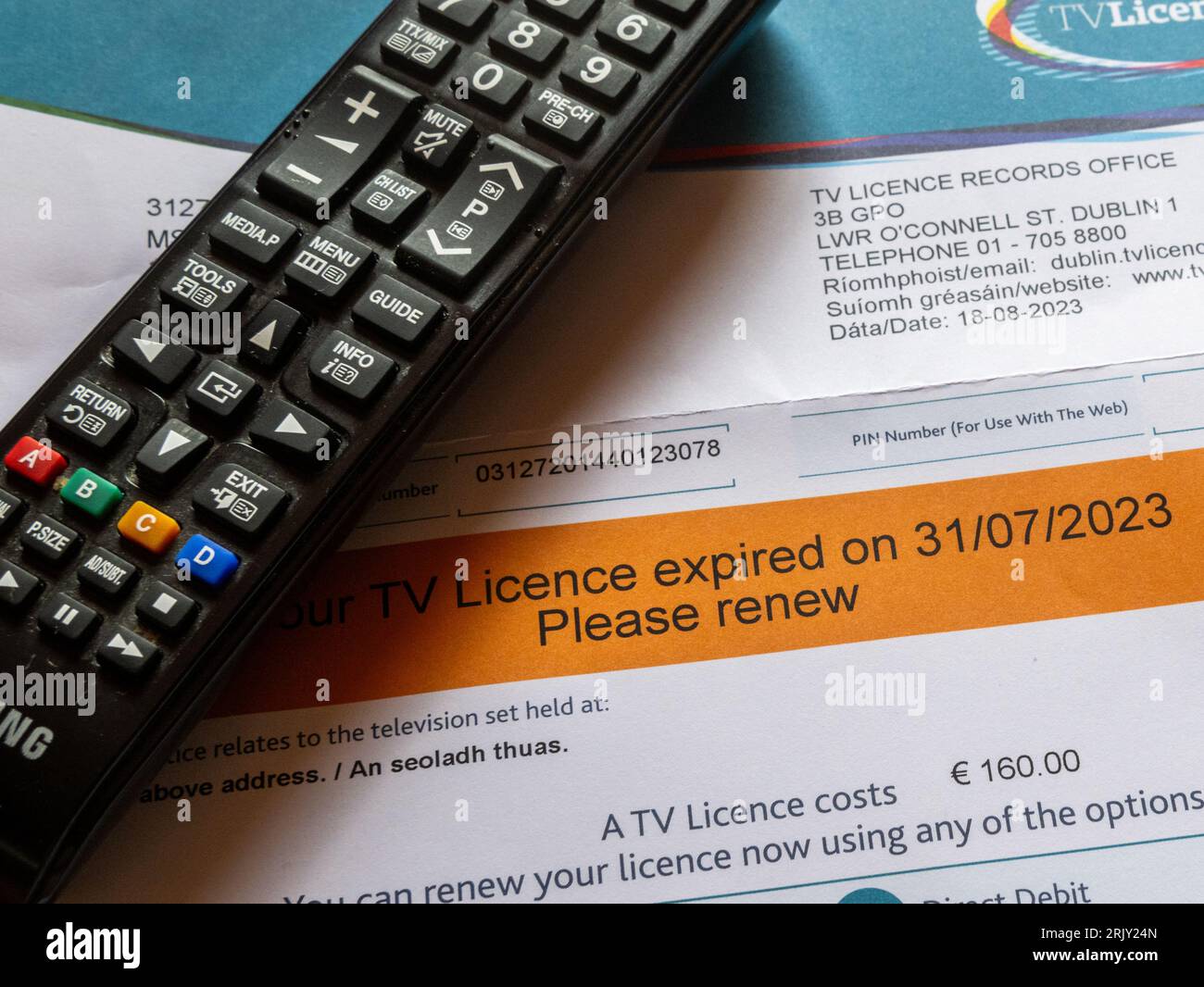 Irish orange TV licence reminder with television remote control. Stock Photo