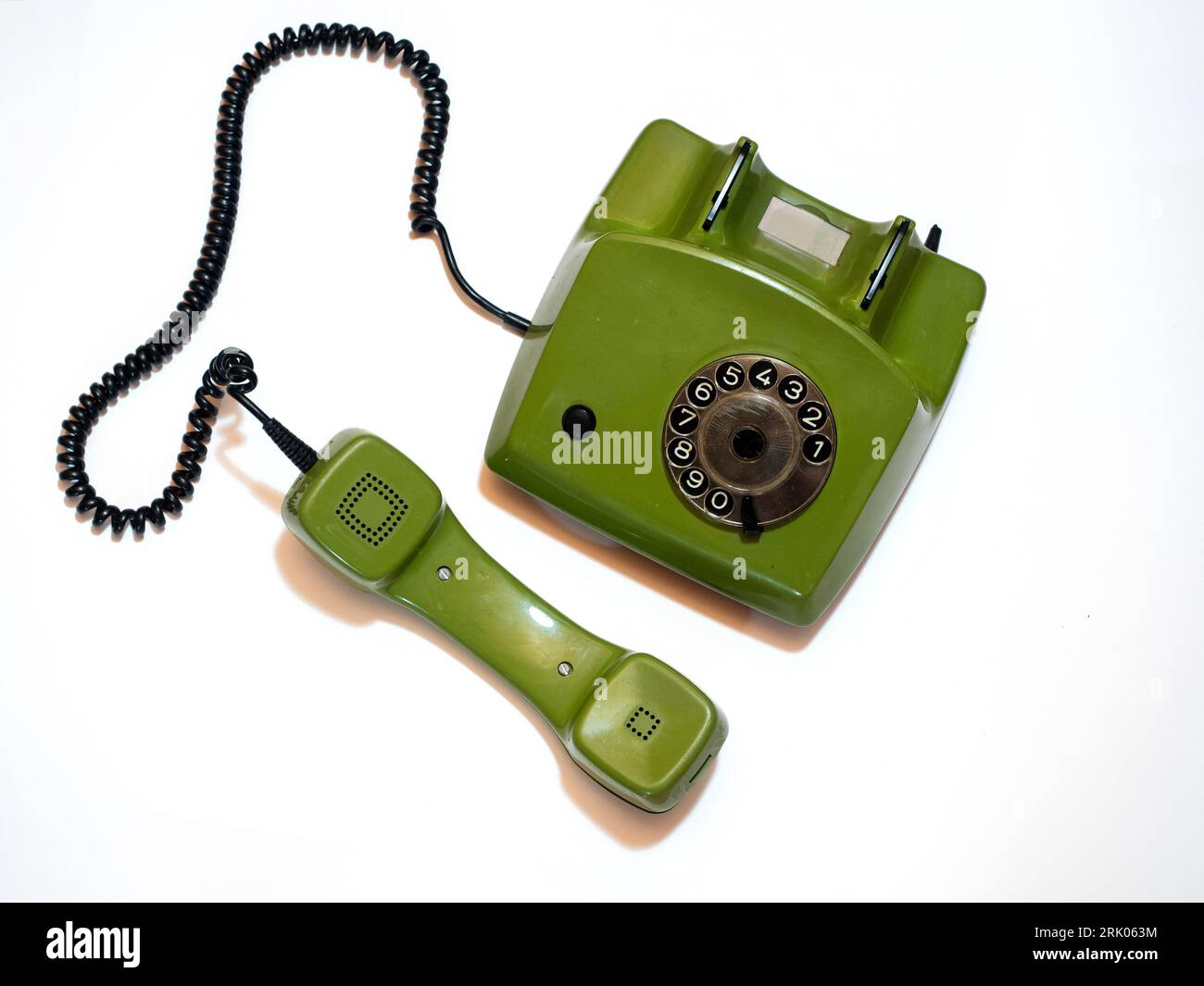 A old green rotary phone is isolated at a white background. Stock Photo