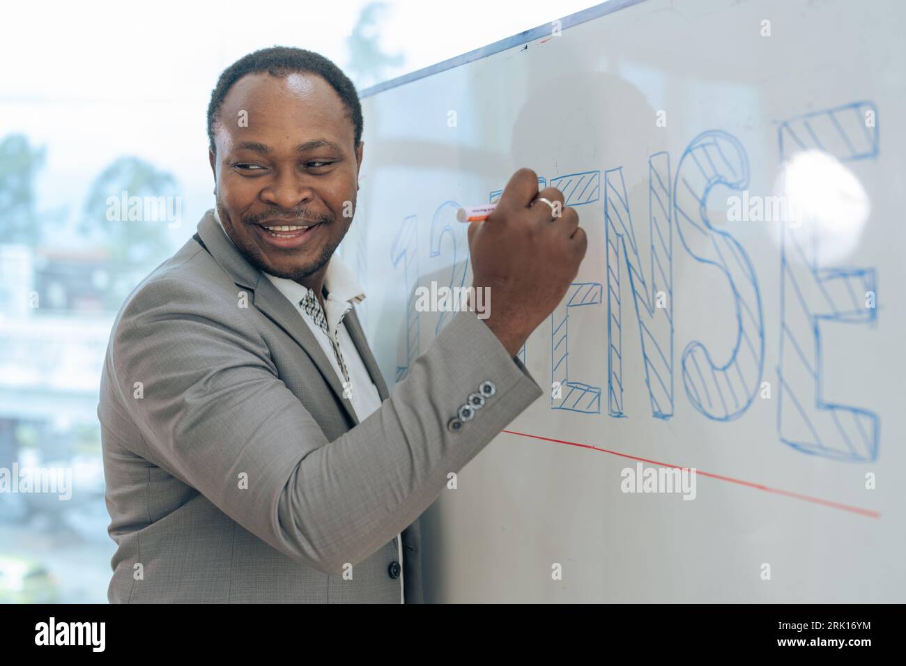 African senior male calculus professor is writing on whiteboard in the ...