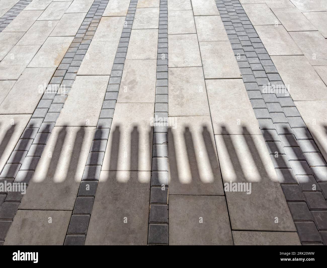 gray concrete block pavement with striped shadow from roof Stock Photo