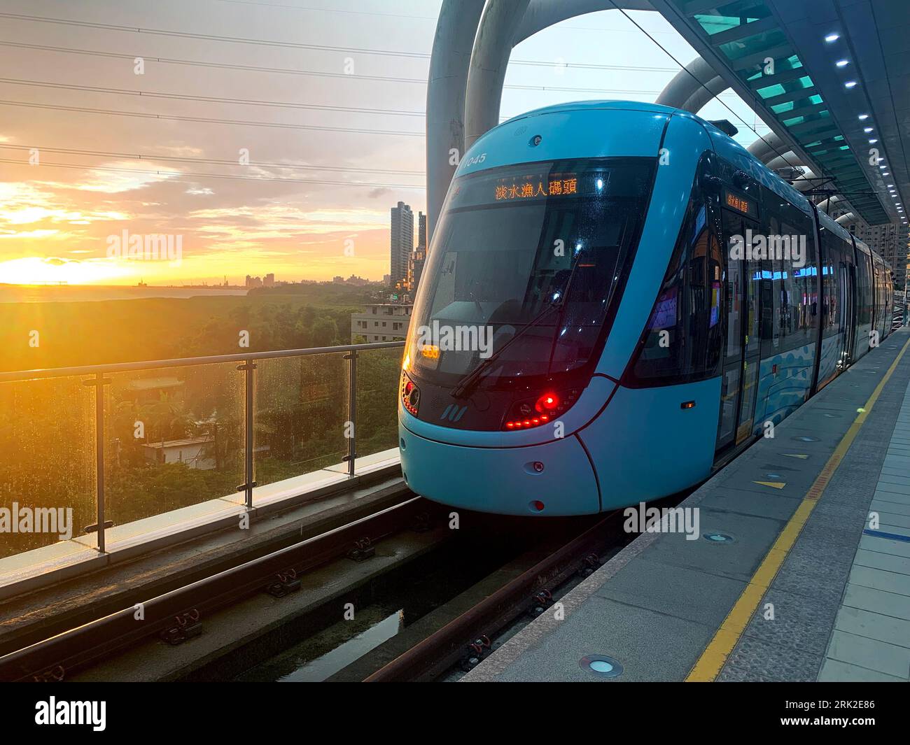 New Taipei City, Taiwan; 2 Jan 2023: A light-rail vehicle to Tamsui Fisherman's Wharf in sunset view. from Hongshulin light rail Station. Stock Photo