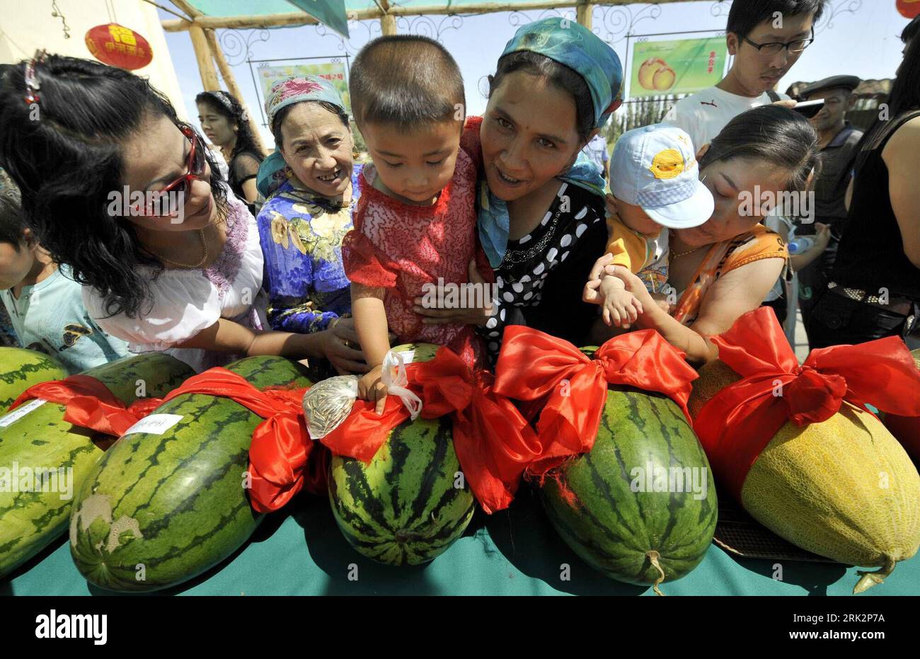 Bildnummer: 53231590  Datum: 29.07.2009  Copyright: imago/Xinhua (090729) -- HAMI(XINJIANG), July 29, 2009 (Xinhua) -- A Uygur woman carrying her child looks at some water melons in a melon contest held in Hami City, northwest China s Xinjiang Uygur Autonomous Region, July 29, 2009. Farmers from all over the city brought their harvests of hami melons, water melons and musk melons to attend the 6th melon contest in Hami on Wednesday, which attracted a great deal of visitors from home and abroad.     (Xinhua/Shen Qiao) (lyi) (2)CHINA-HAMI-MELON-CONTEST (CN)  PUBLICATIONxNOTxINxCHN  Melonen Wettb Stock Photo