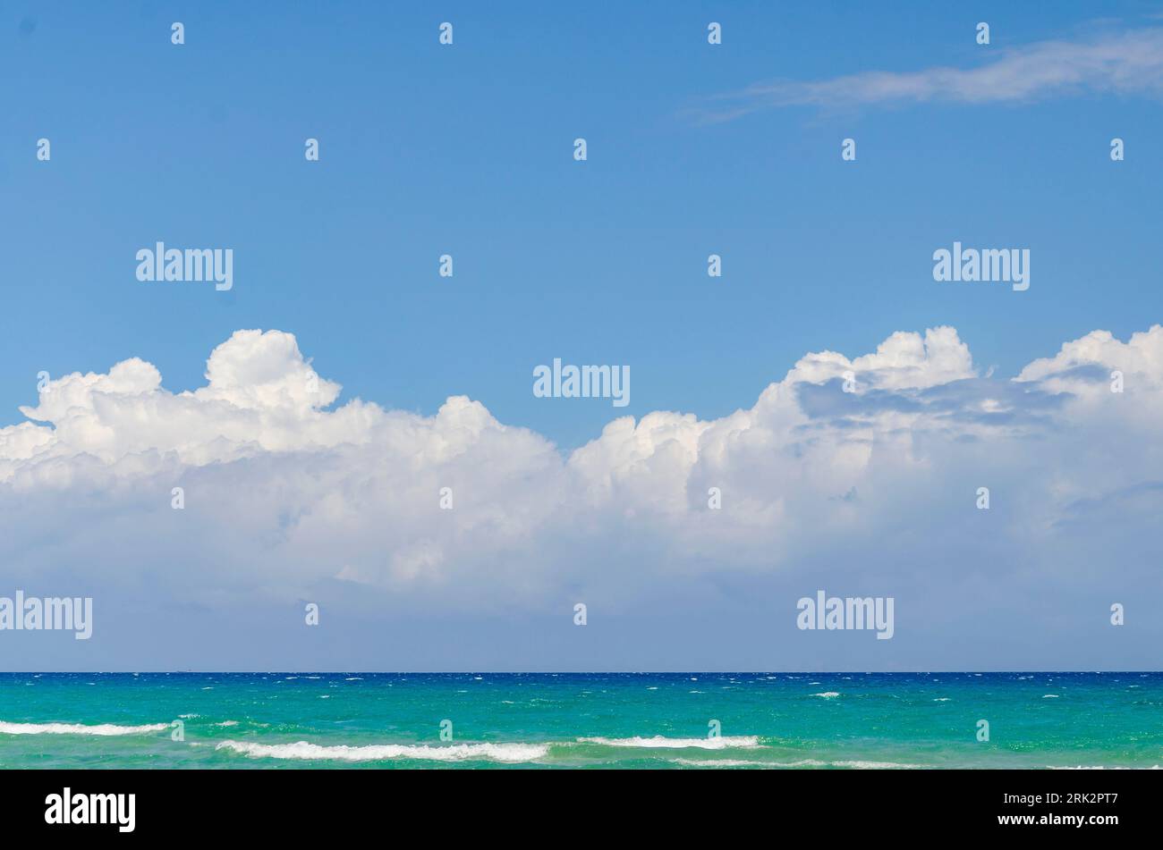 Blue sky and fluffy clouds over a blue sea Stock Photo - Alamy