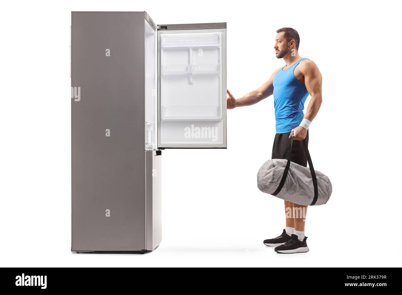 Fit man holding a sports bag and opening an empty fridge isolated on