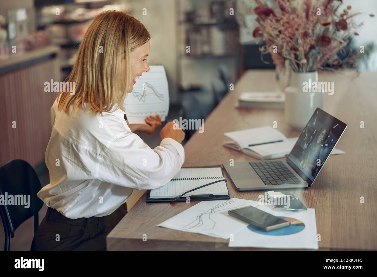 Woman analyst working with documents during video conference while sitting in modern coworking Stock Photo