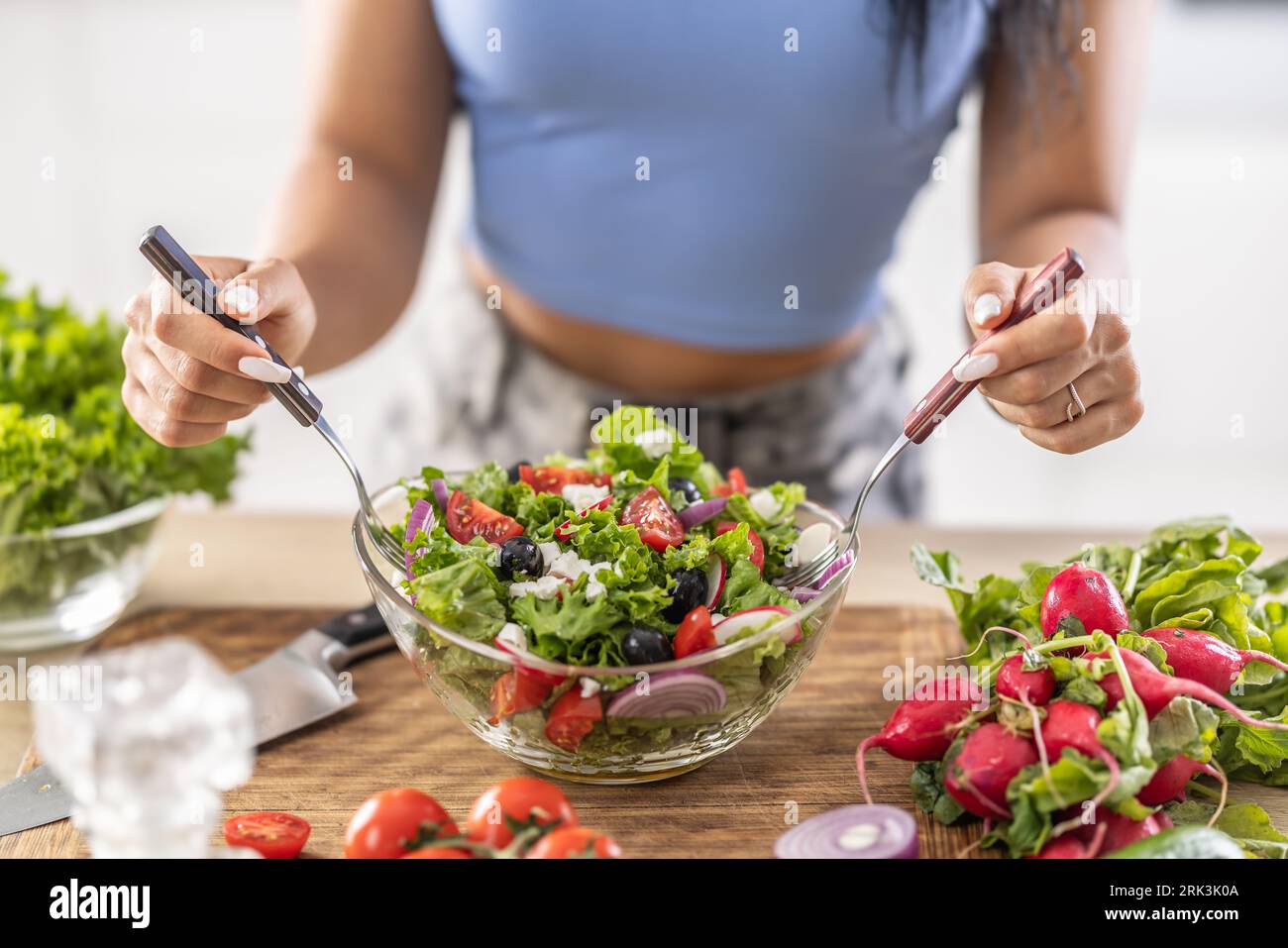 Female hands mixing a healthy spring salad made from various ingredients. Concept of healthy lifestyle. Stock Photo