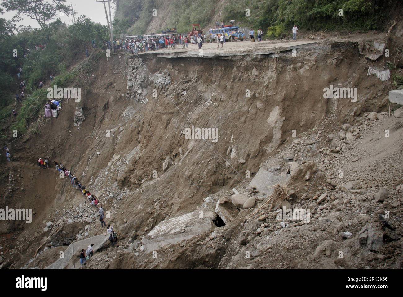 Bildnummer: 53525526  Datum: 12.10.2009  Copyright: imago/Xinhua (091012) -- MANILA, Oct. 12, 2009 (Xinhua) -- Stranded commuters walk along a foot path below a collapsed highway in the town of Taloy Sur, Tuba, near Baguio City of Benguet Province, in north Philippines, on Oct. 12, 2009. Search and rescue teams struggled to reach areas of the northern Philippines cut off by storm-triggered landslides and flooding that have left more than 600 dead, officials said. (Xinhua/Roel Zaragoza) (zw) (1)THE PHILIPPINES-TROPICAL STORM-AFTERMATH PUBLICATIONxNOTxINxCHN Naturkatastrophen Erdrutsch Philippin Stock Photo