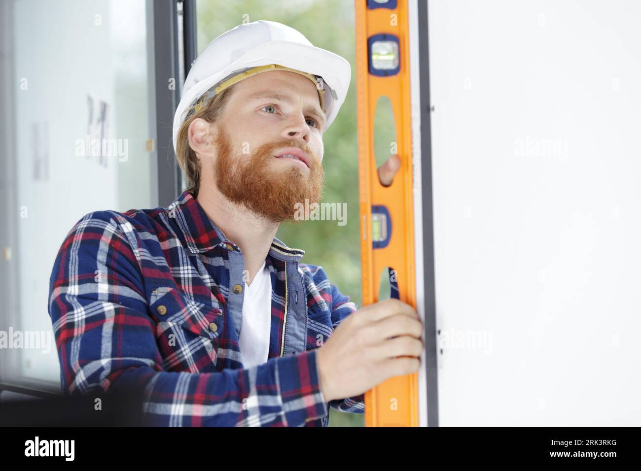 builder man checking vertical surface with bubble level Stock Photo
