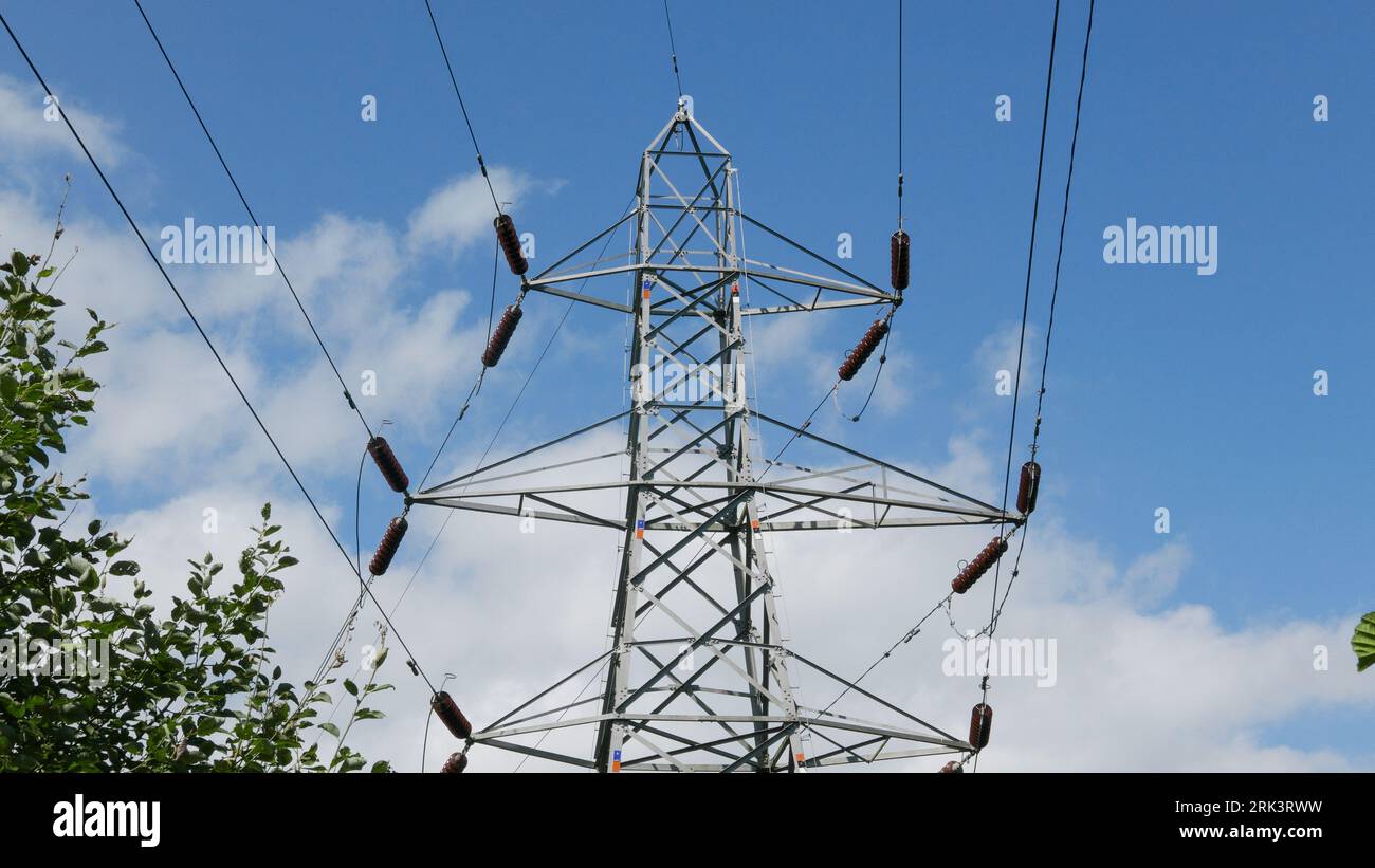 Pylon and powerlines against blue sky.. UK.  2023 Stock Photo