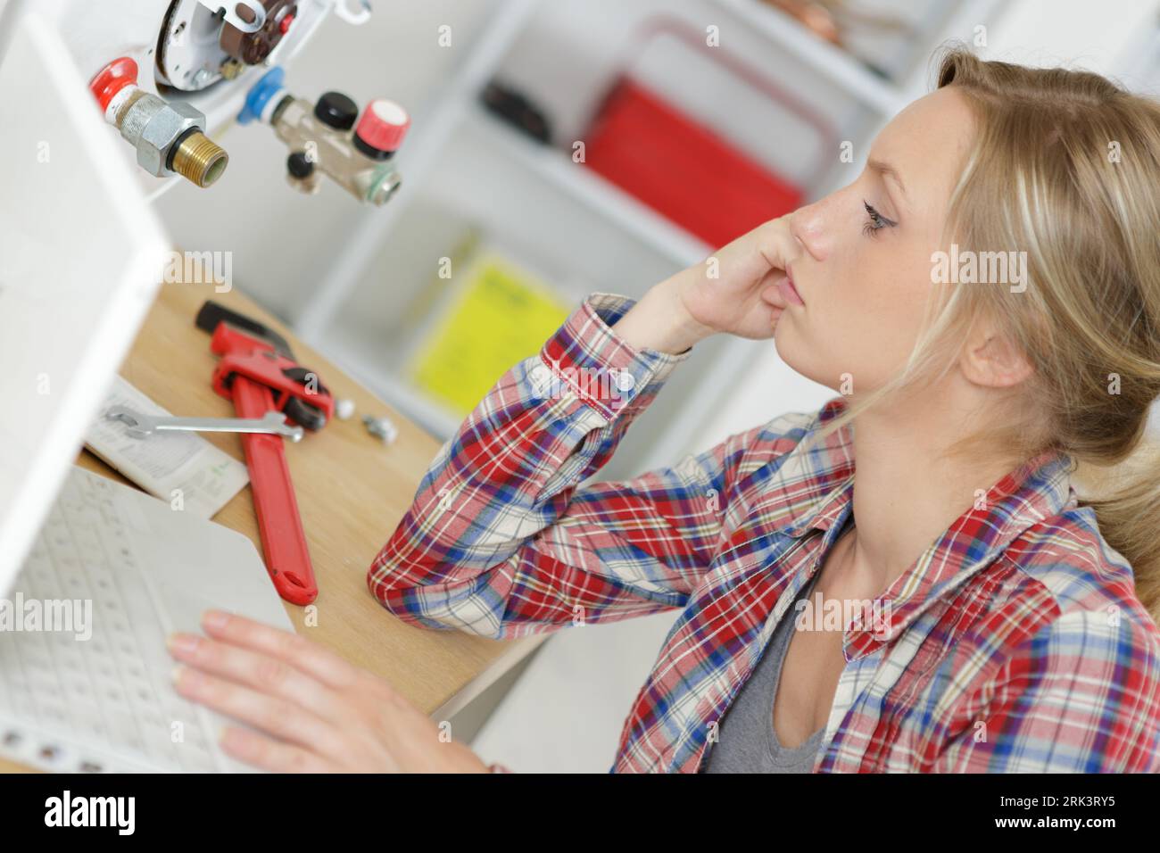 female technician servicing a boiler using computer Stock Photo