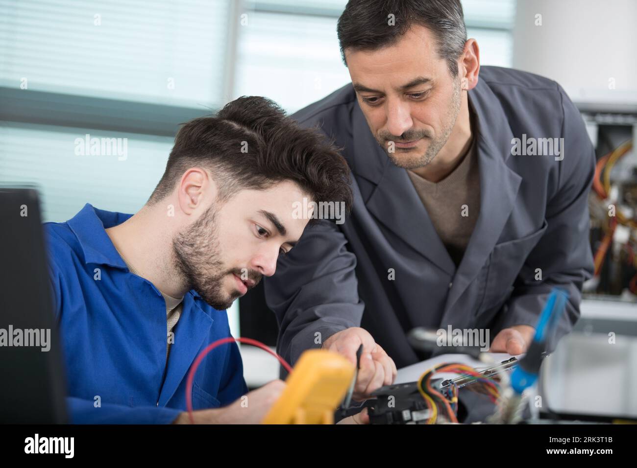 supervisor guiding apprentice using a multimeter Stock Photo