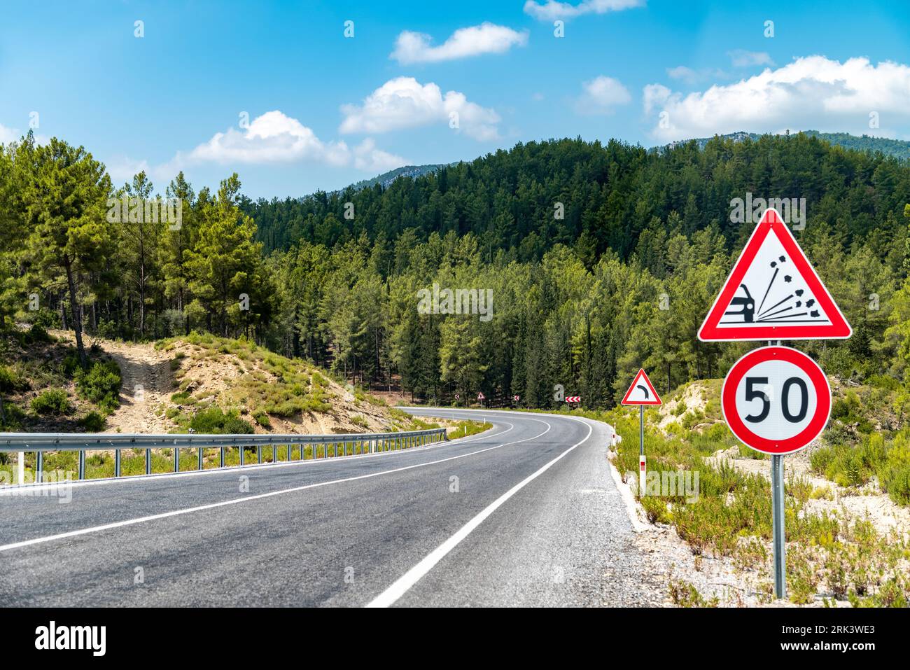 50 km/h speed limit and warning signs on the winding asphalt road going