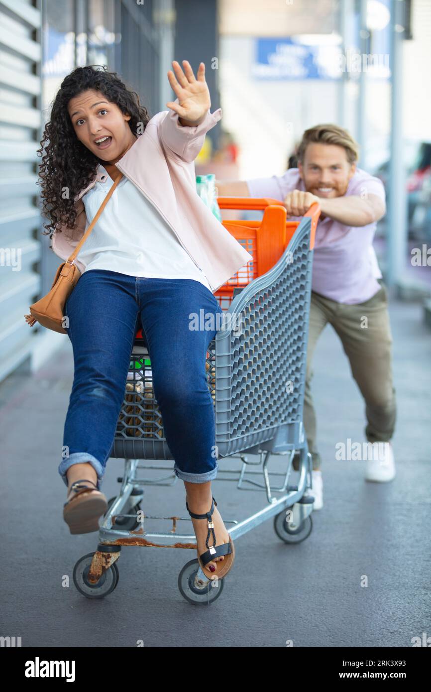 young happy man pushing shopping cart with his girfriend inside Stock ...