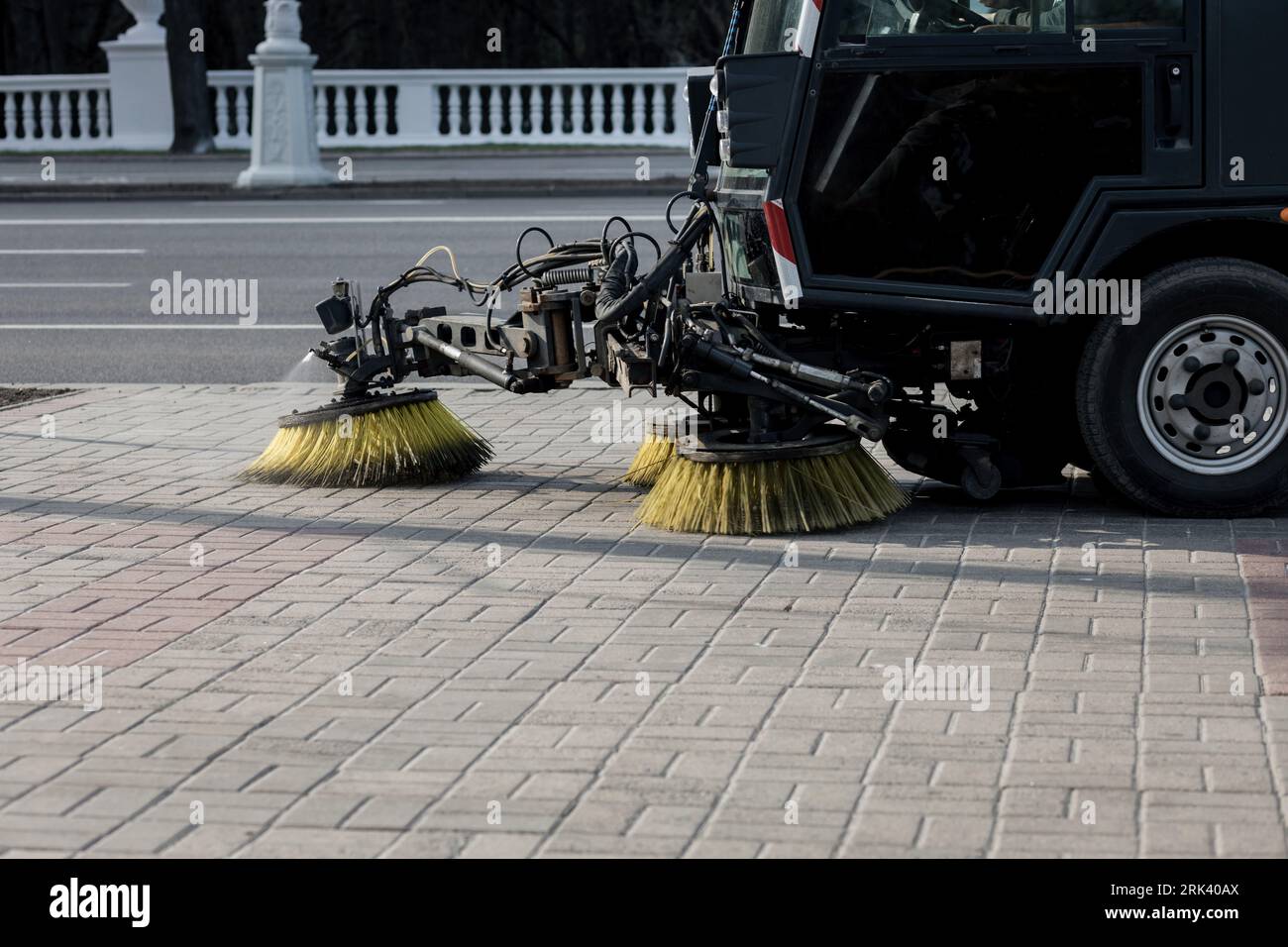 Sweeping machine brushes clean the city sidewalk. city background with