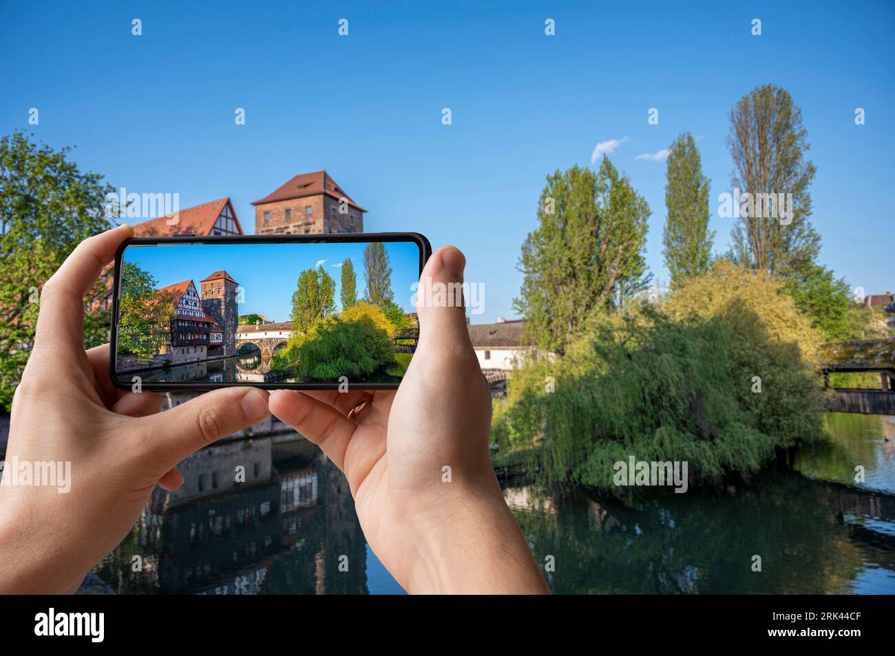 Tourist taking photo of old medieval bridge over Pegnitz river in Nuremberg, Germany. Hangman's Bridge. Stock Photo