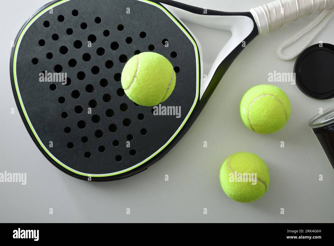 Black and white paddle tennis racket and ball pot on a white table. Top view. Stock Photo