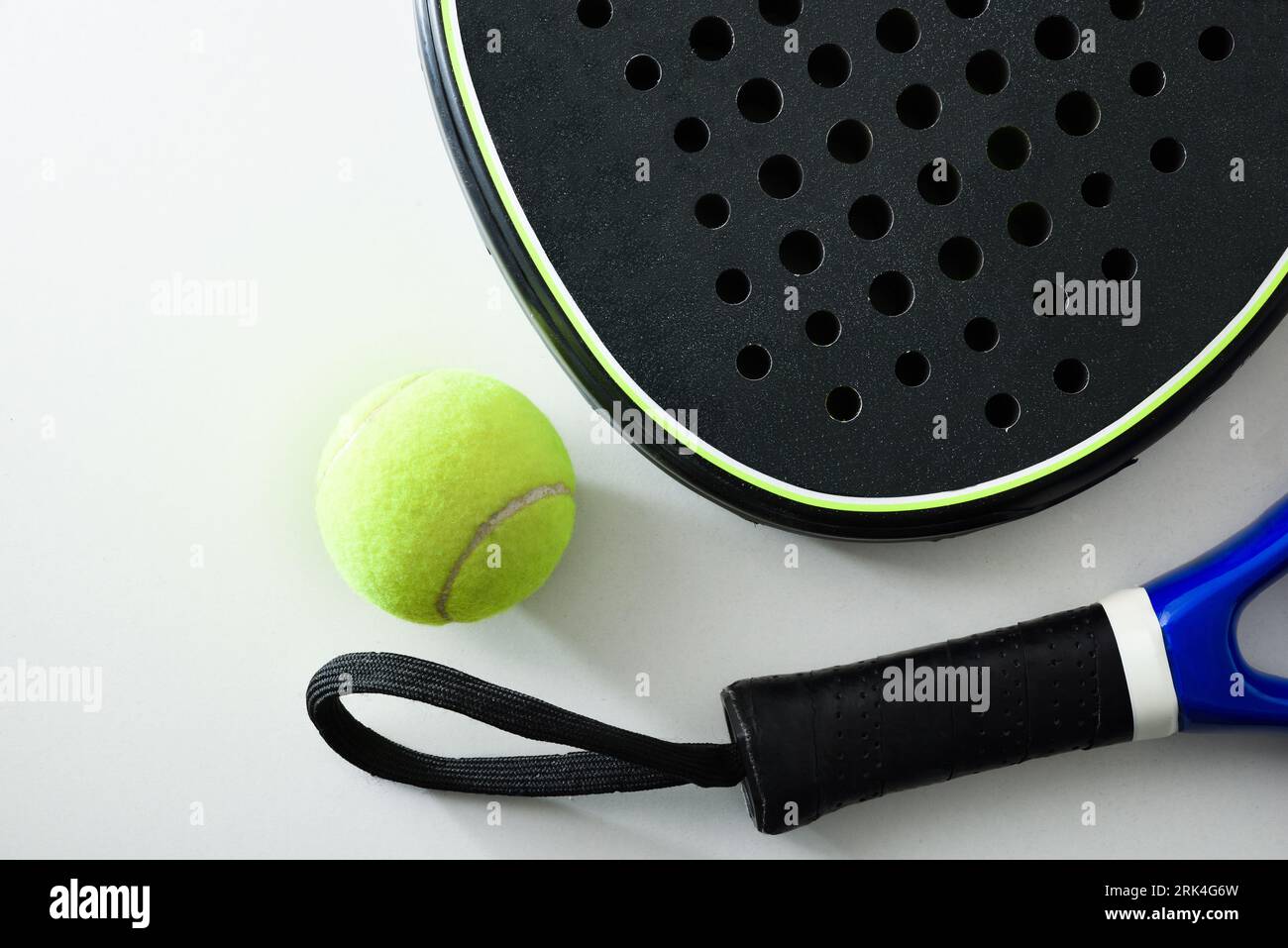 Two blue and black paddle rackets detail on white table with a ball. Top view. Stock Photo