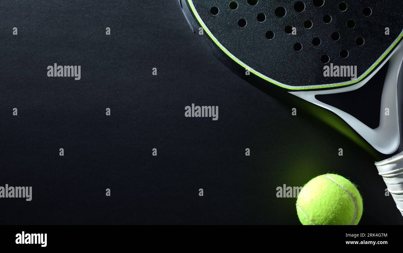 Detailed background of black and white padel racket and ball on black background. Top view. Stock Photo