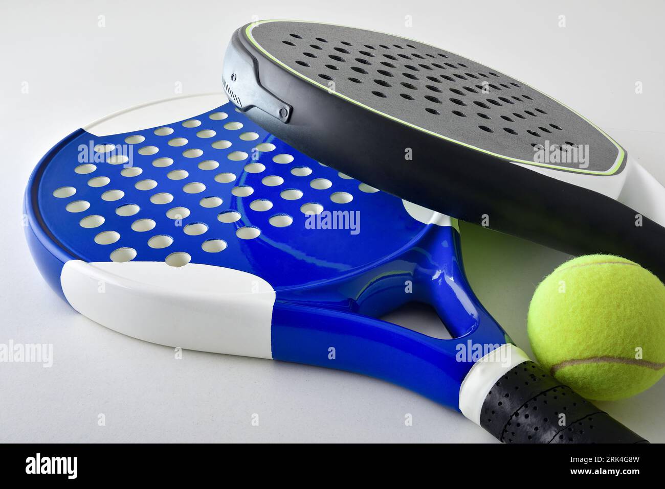 Background with two blue and black paddle rackets on a white table with ball. Elevated view. Stock Photo