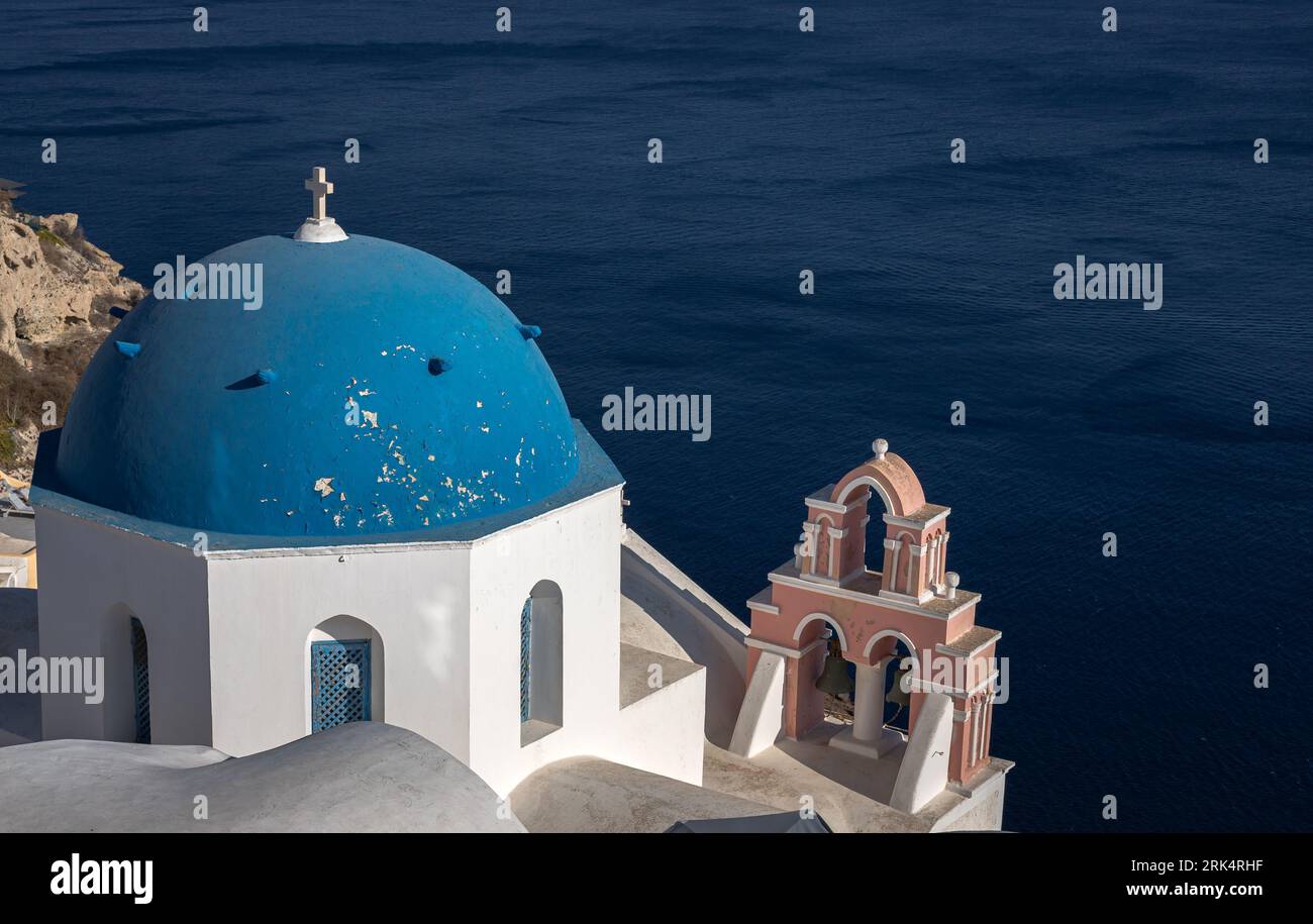 A beautiful blue domed church over the water in Santorini, Greece Stock Photo