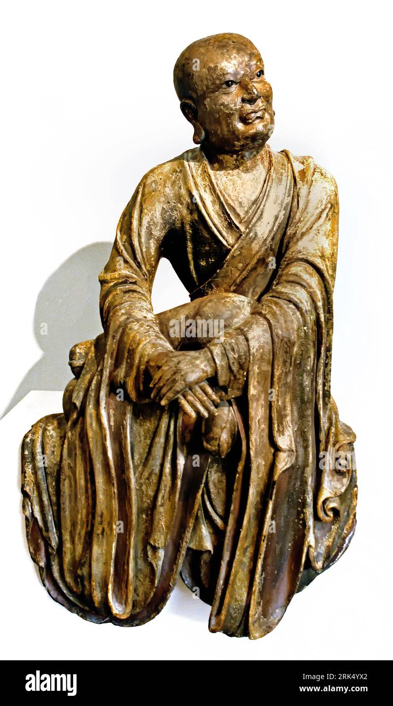 Temple Guardian 14th century Japan Japanese Museum  ( placed at the entrance to a temple to ward of evil )  Located at Rijksmuseum  Amsterdam. wood (plant material), h c.239.5cm × w 131.5cm × d 62cm  Temple guardians are placed at the entrance to a temple to ward off evil. Each of these figures holds a vajra for crushing ignorance. Their open and closed mouths represent a and un, the first and final syllables of Siddham (a script used to write Sanskrit): these syllables symbolize all spoken sounds and scripts, thus all knowledge. Worshippers who enter the temple precinct through t Stock Photo