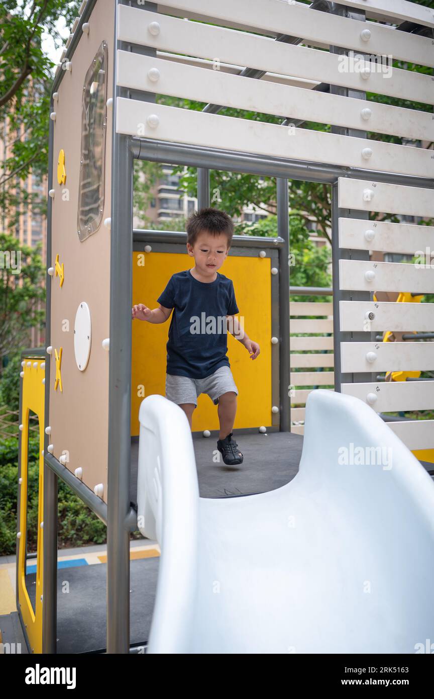 A two year old and curious baby boy enjoys discovering the game on the slide. Stock Photo