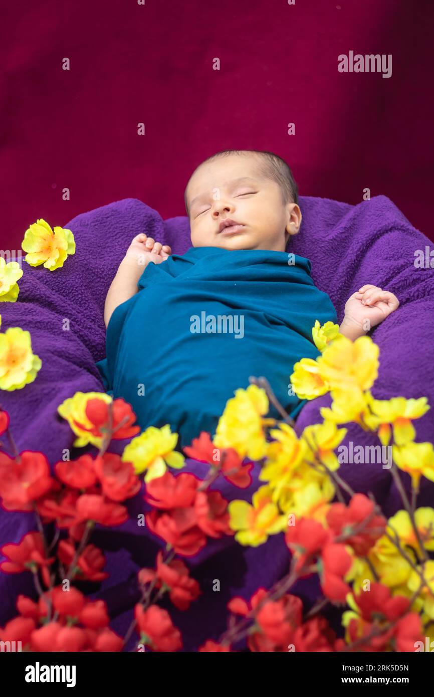 cute newborn baby sleeping in baby wrap with flowers in unique style