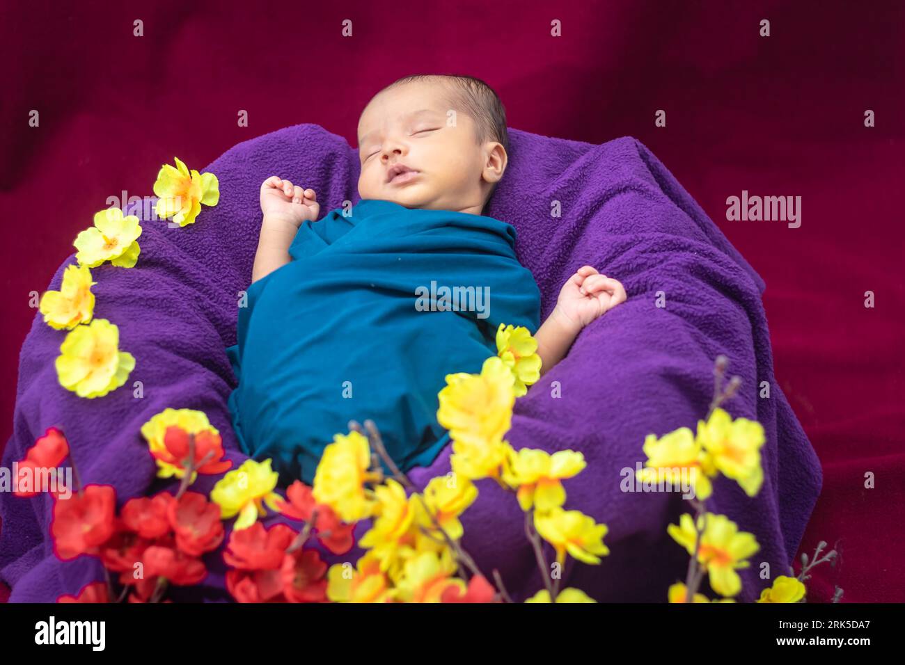 cute newborn baby sleeping in baby wrap with flowers in unique style