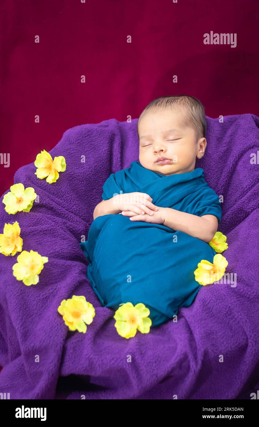 cute newborn baby sleeping in baby wrap with flowers in unique style