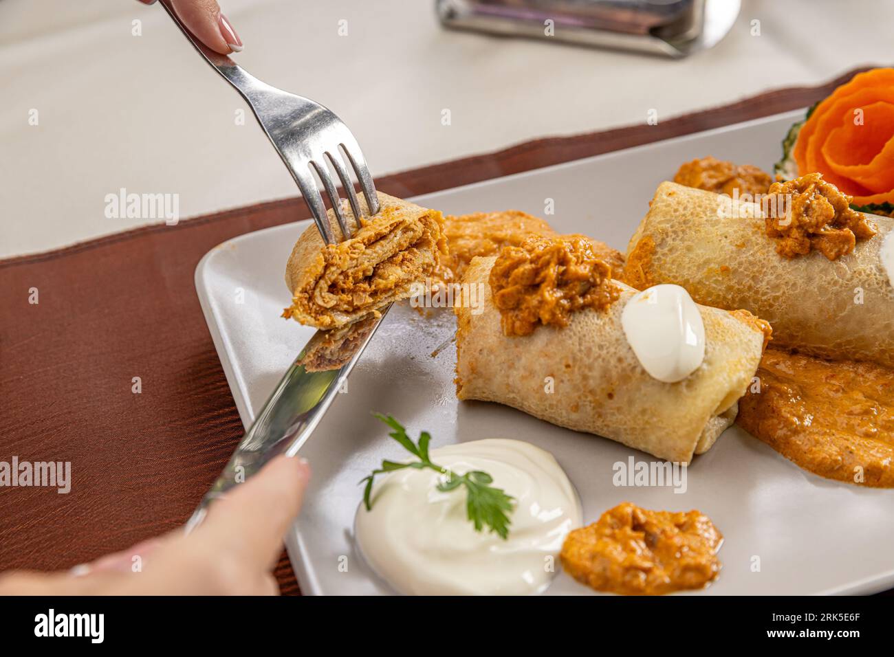 Pancake roll filled with veal stew and topped with sour cream mixed with gravy Stock Photo