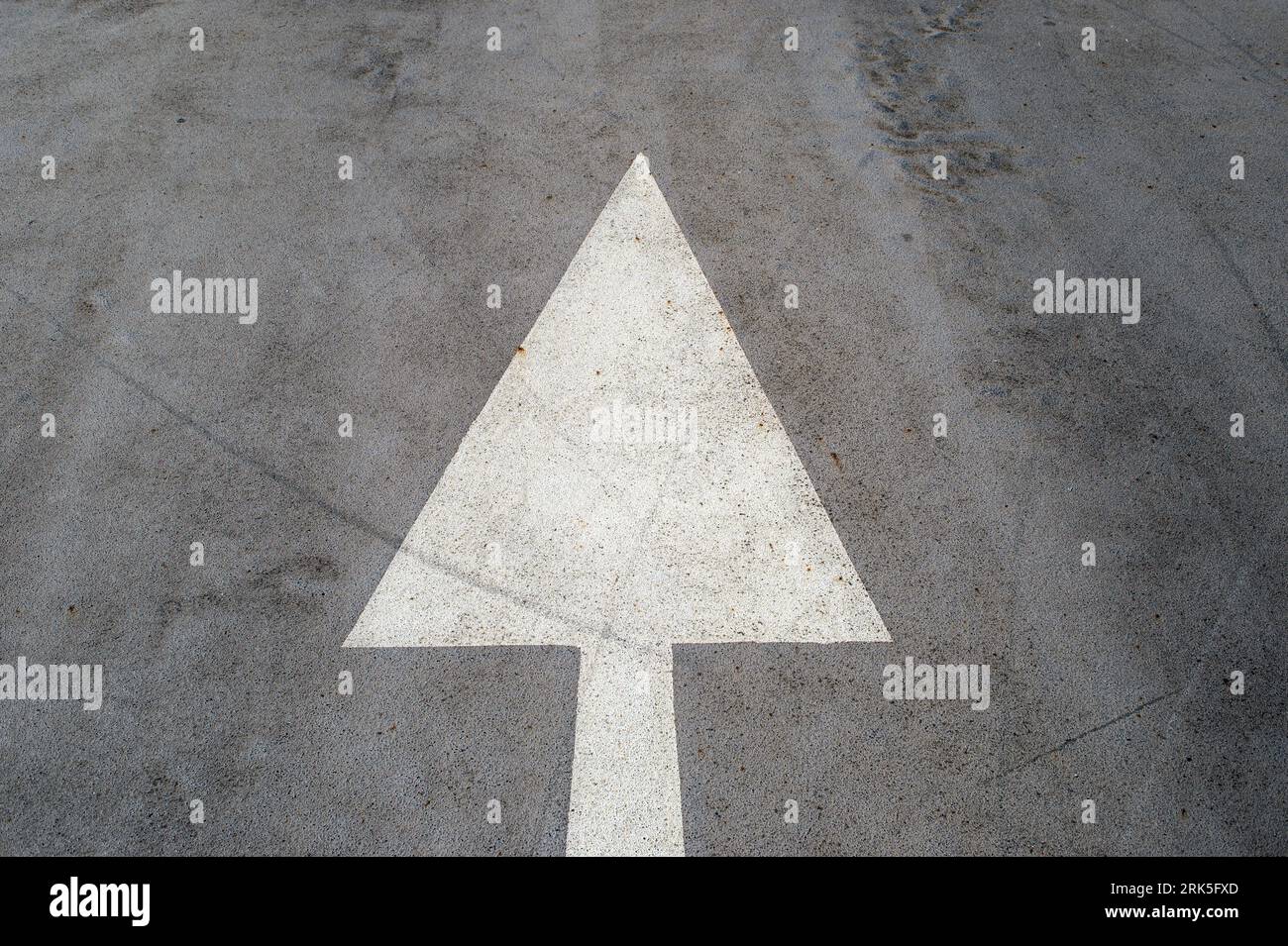 White painted arrow on a road suface, straight ahead. Stock Photo