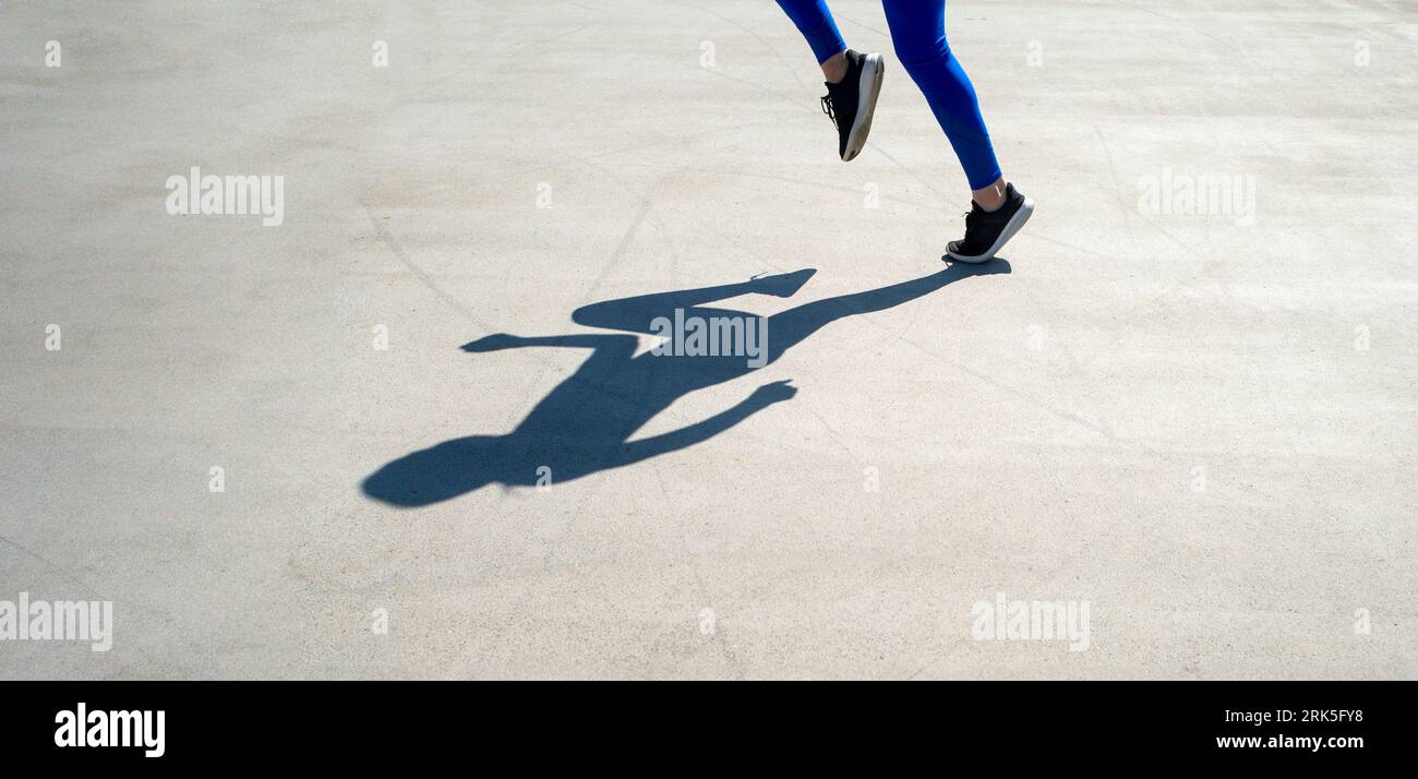 shadow of a woman athlete jogger in road Stock Photo